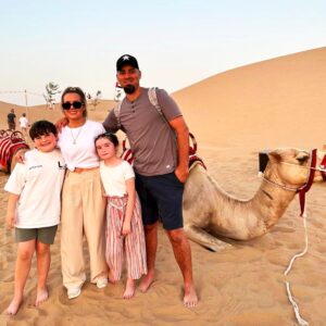 four-people-standing-in-front-of-a-camel
